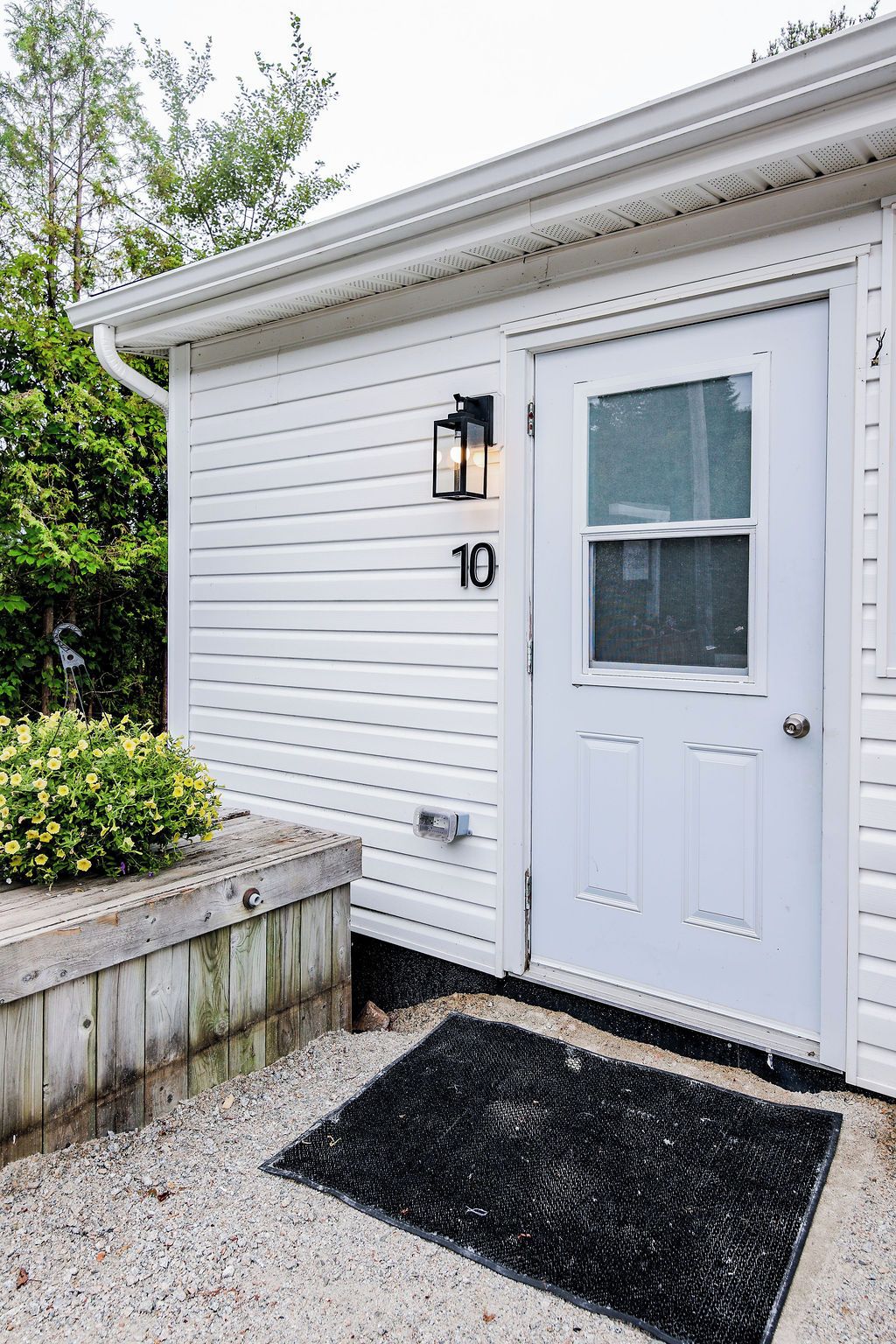 A white single-story building with a front door, a mailbox, and a number '10' sign.