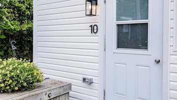 A white single-story building with a front door, a mailbox, and a number '10' sign.