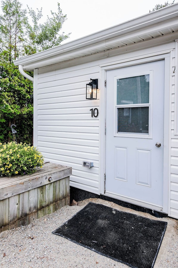 A white single-story building with a front door, a mailbox, and a number '10' sign.