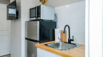 A modern kitchen with a stainless steel refrigerator, a microwave, and a sink with a wooden countertop.