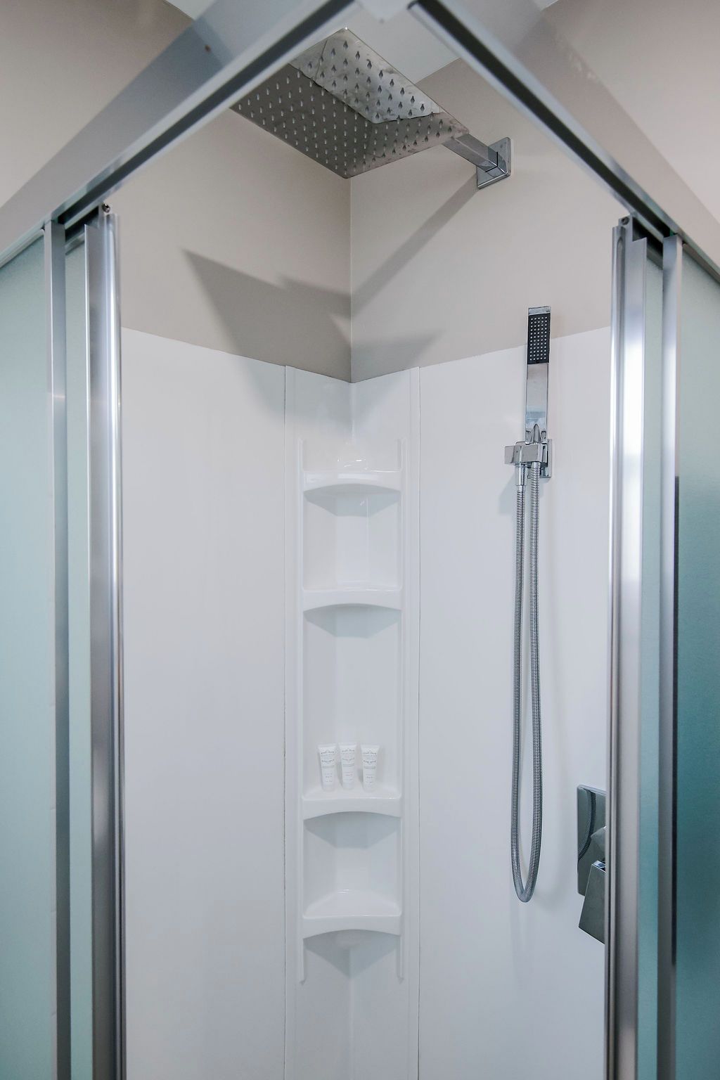 A modern shower enclosure with a handheld showerhead and a wall-mounted showerhead.