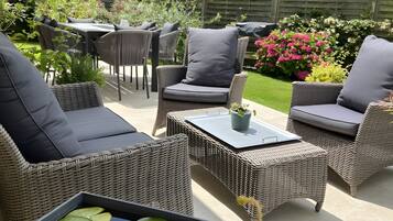Une terrasse extérieure aménagée avec des meubles en osier, une table et un bassin à fleurs.