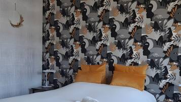 Un lit bien fait, avec du linge de lit blanc et des serviettes pliées, un papier peint à motifs avec des dessins abstraits et un élément décoratif mural texturé.