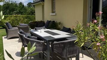 Une terrasse extérieure avec une table à manger, des chaises et un pot de fleurs.