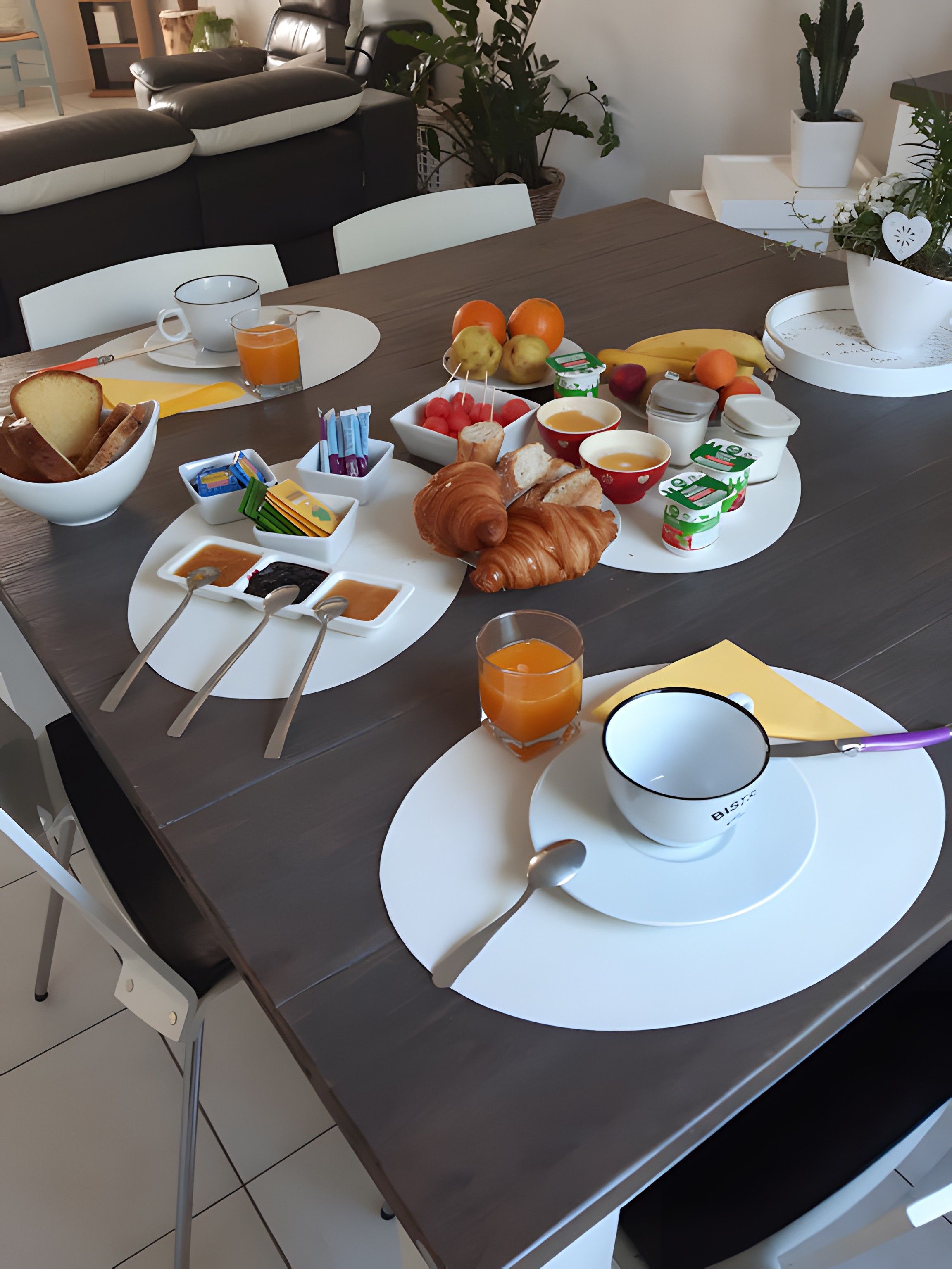 Een ontbijttafel gedekt met croissants, fruit en drankjes, wat duidt op een hotelontbijtservice.