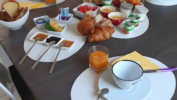 Een ontbijttafel gedekt met croissants, fruit en drankjes, wat duidt op een hotelontbijtservice.