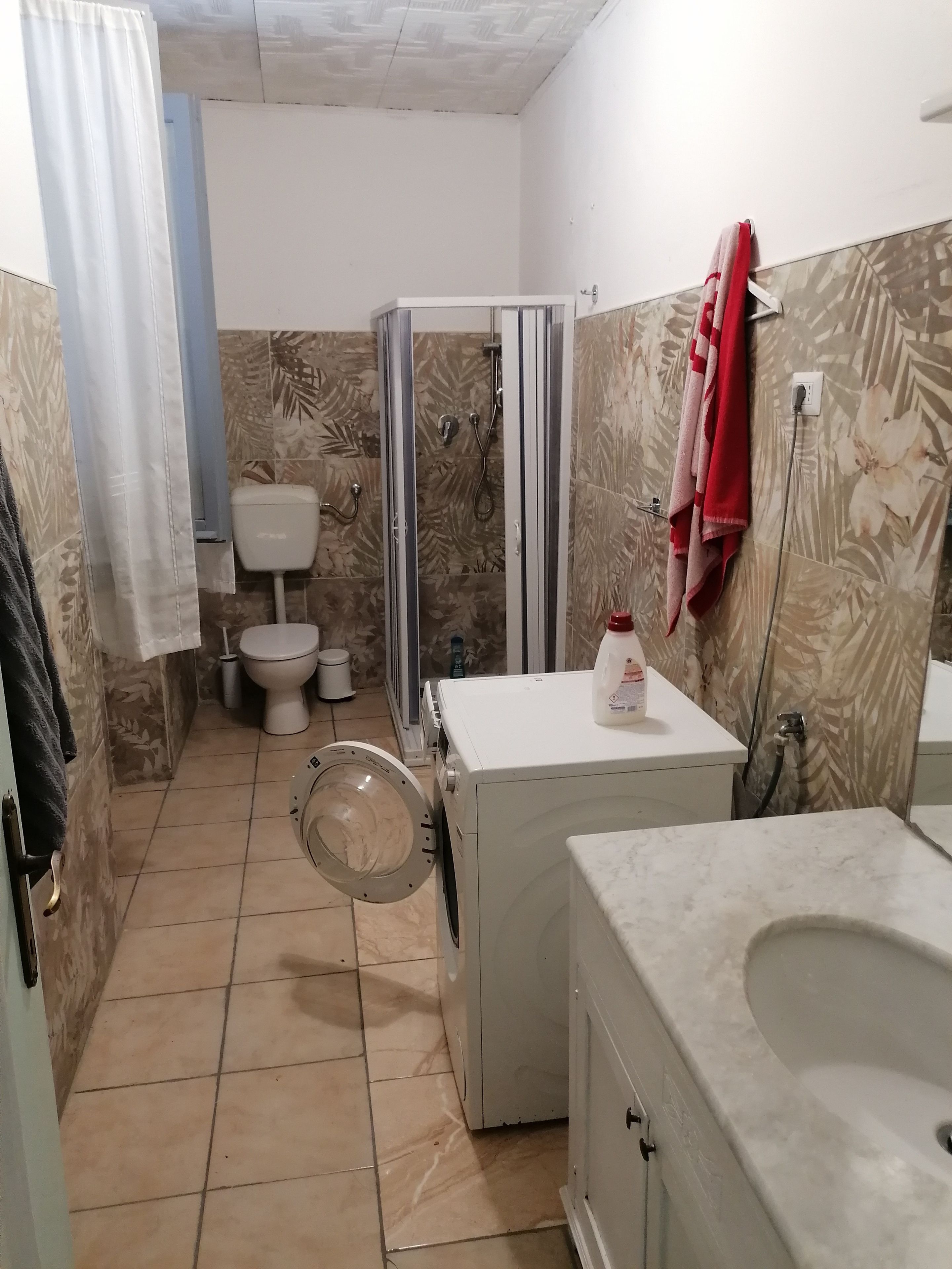 Ein Badezimmer mit Toilette, Dusche und Waschmaschine.
