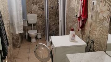 Ein Badezimmer mit Toilette, Dusche und Waschmaschine.