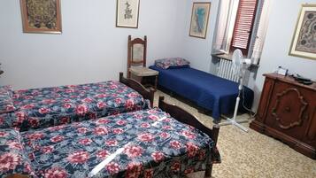 Ein Schlafzimmer mit zwei Betten, einem Sessel, einem Heizkörper und einem Holzschrank.