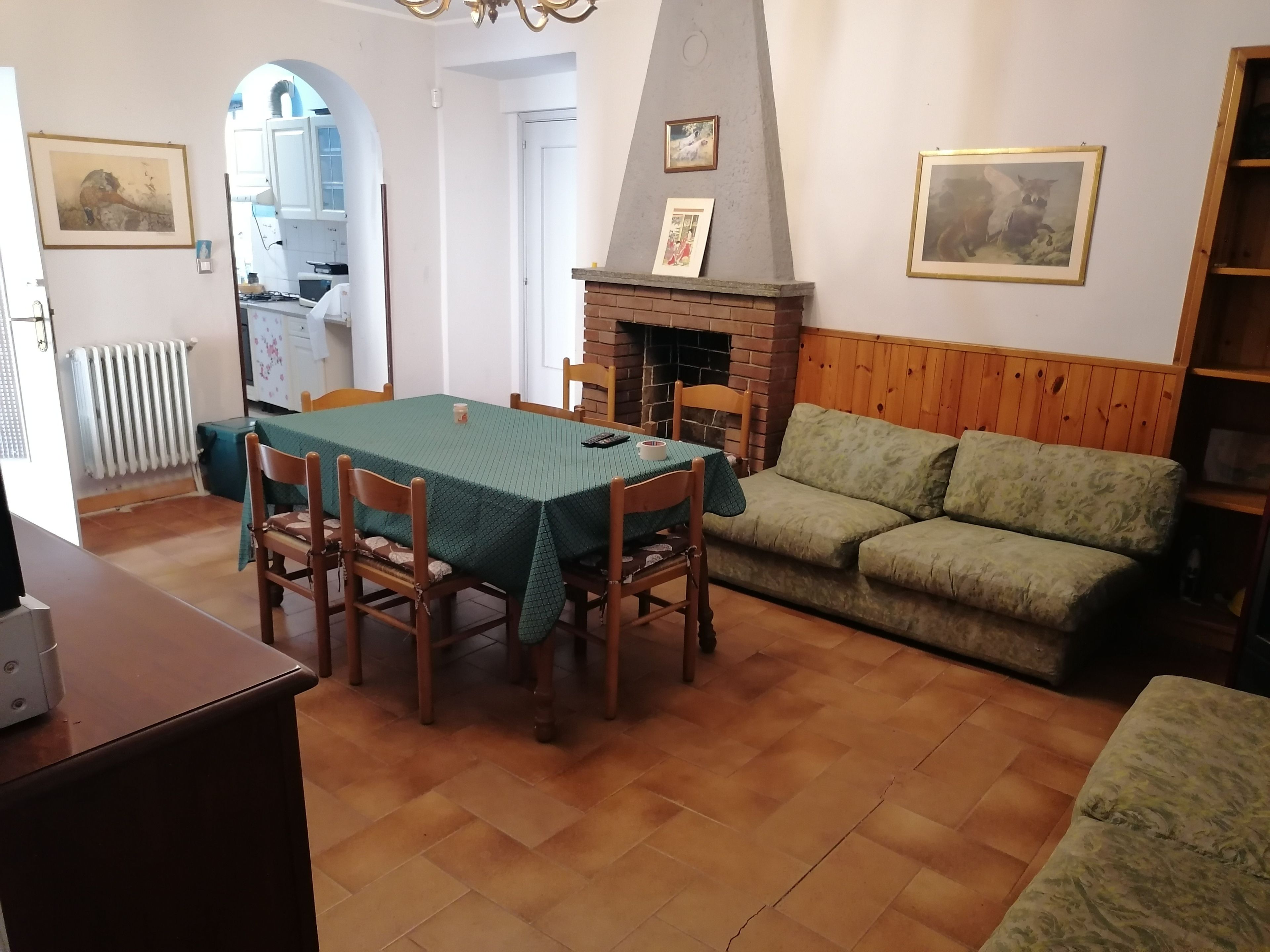 Ein Essbereich mit Tisch und Stühlen, einem Kamin, einer Couch und einer Küche im Hintergrund.