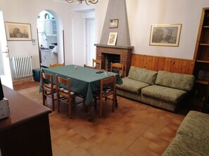 Ein Essbereich mit Tisch und Stühlen, einem Kamin, einer Couch und einer Küche im Hintergrund.