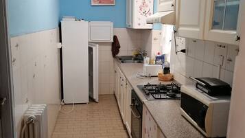 A kitchen with white cabinets, a refrigerator, a stove, and a microwave.