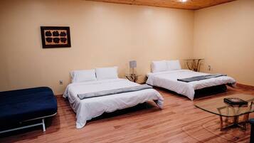 A room with two beds, a small table, and a wall-mounted picture.