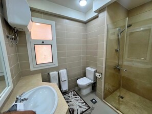 Ein Badezimmer mit einer Duschkabine, einer Toilette und einem Waschbecken.