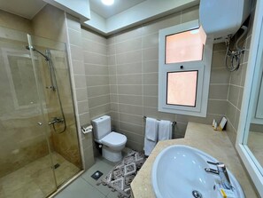 Ein Badezimmer mit Duschkabine, Toilette, Waschbecken und Handtuchhalter.