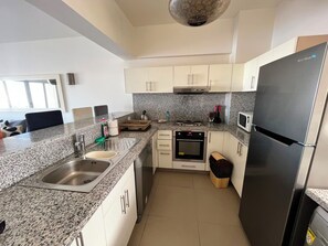 A modern kitchen with granite countertops, stainless steel appliances, and white cabinetry. - VESTA - Luxury APT - 2BR - Joubal (El Gouna)