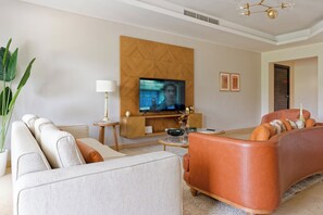 Ein Wohnzimmer mit einer Couch, einem Fernseher, einer Lampe und einer Zierverkleidung an der Wand.