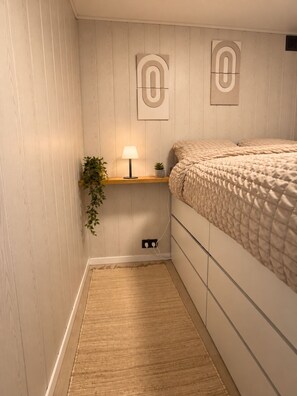 A bedroom with a bed, bedside table, lamp, wall art, and a small plant. - Châtel - Charming, renovated apartment with a balcony offering mountain views - Sleeps 4 (chatel)