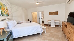 A bedroom with a bed, bedside tables, a desk, a television, and artwork on the walls. - Ocean View Retreat • Steps to Private Beach • Free Weekly Maid Service (Sosúa)