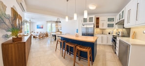 Una cocina moderna con una isla central, electrodomésticos de acero inoxidable y taburetes de madera.