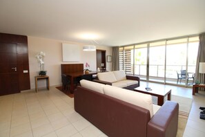A modern living room with a sofa, a dining table, and a large window. - Apartment Villa das Lagoas - by D´alma (Albufeira)