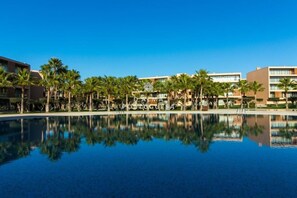 Ein Hotel mit mehreren Gebäuden, einem Schwimmbad und Palmen.