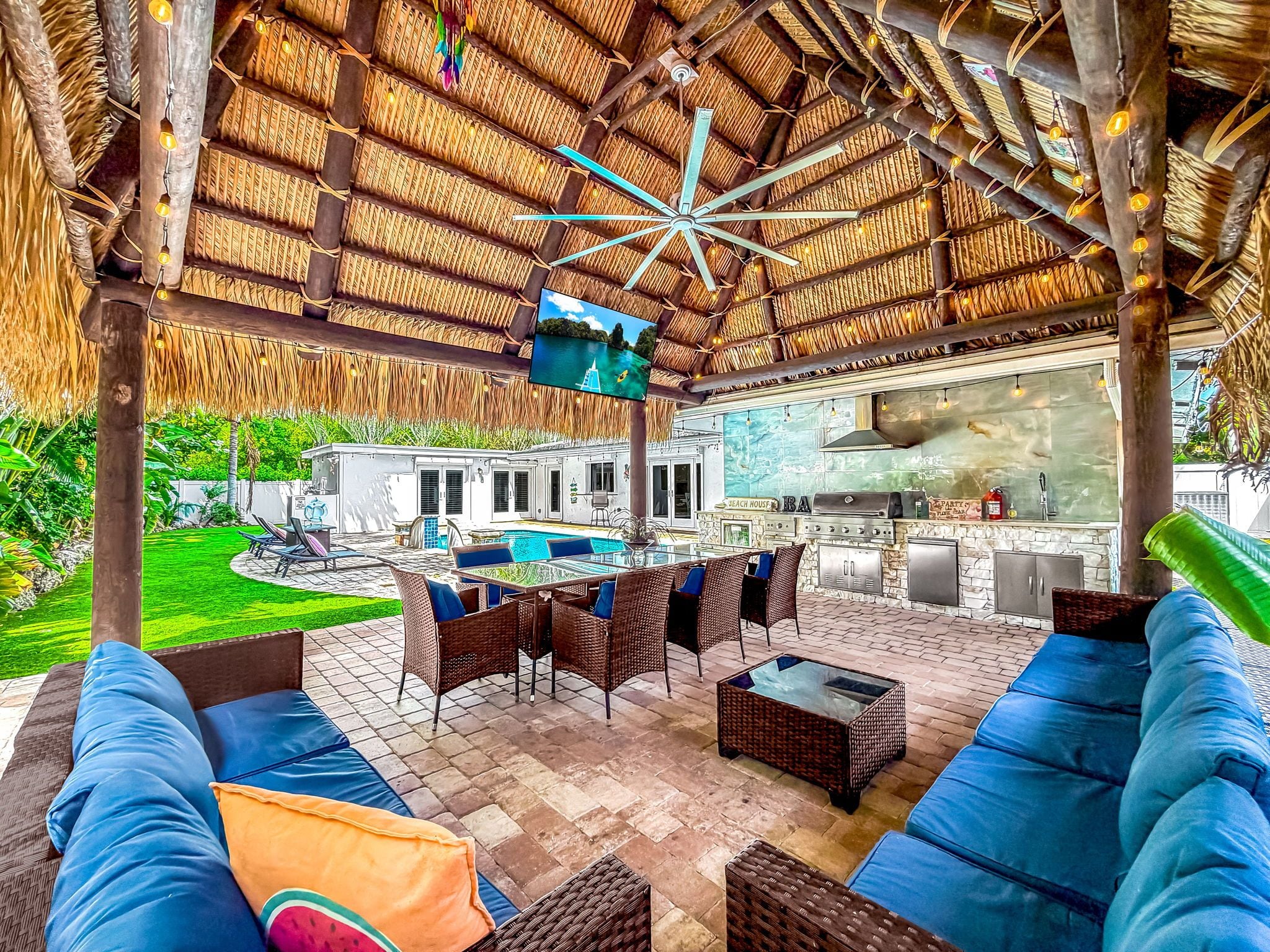 Eine Außenpatio mit Korbmöbeln, einem Pool und einer Bar.