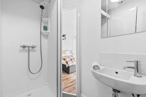 A modern bathroom with a shower, a sink, and a mirror. - Stylish studio near Leeds City Centre - Room 3 (Leeds)