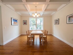 Un comedor con una mesa y sillas de madera, una araña y obras de arte enmarcadas en las paredes.