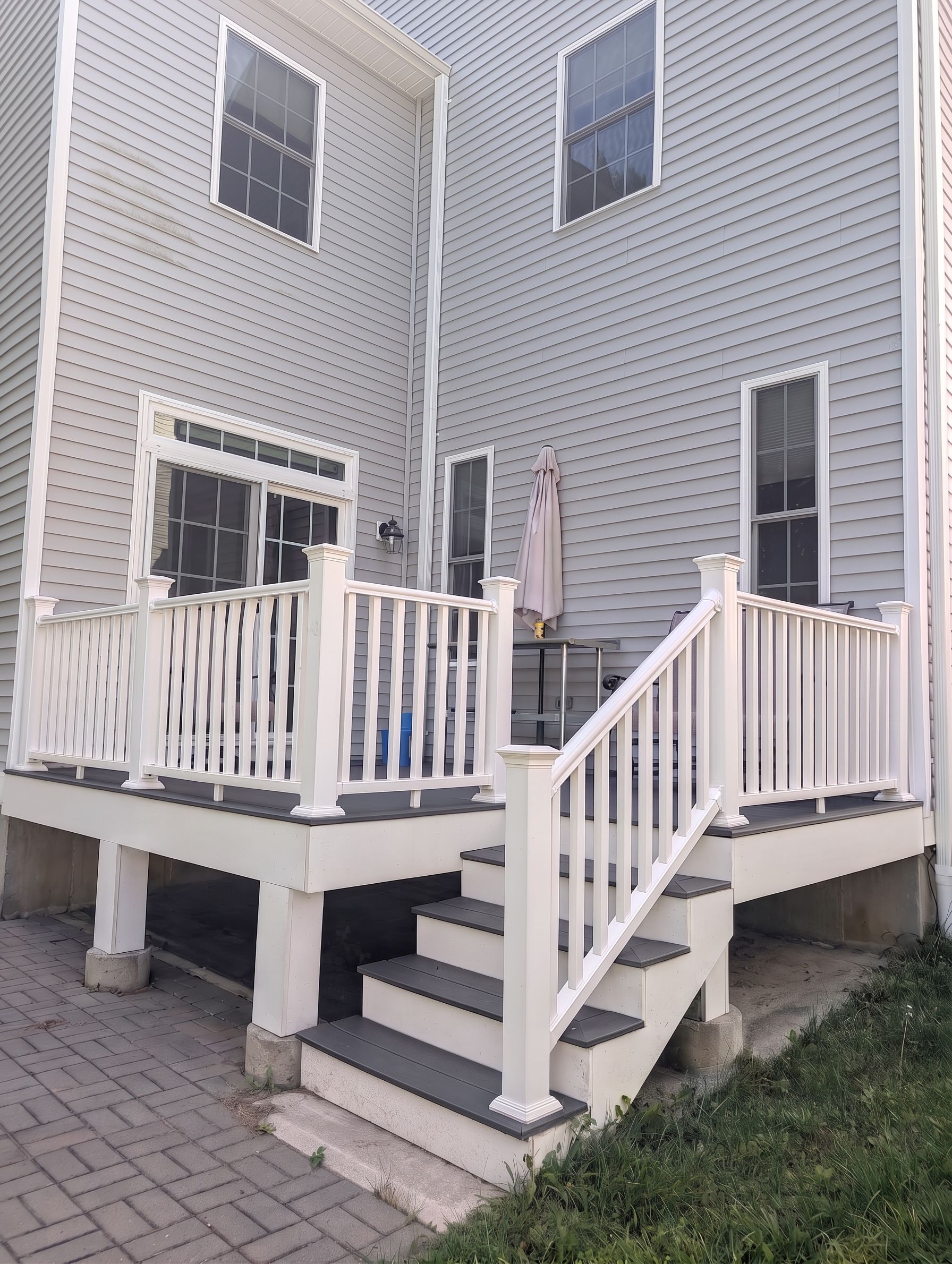 Une maison à deux étages avec un porche à l’avant, un escalier et un petit espace extérieur aménagé pour s’asseoir.