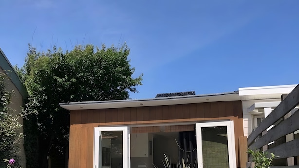 Ein modernes Haus mit Holzfassade, einem Glastür-Eingang und einem Kiesweg, der zur Tür führt.