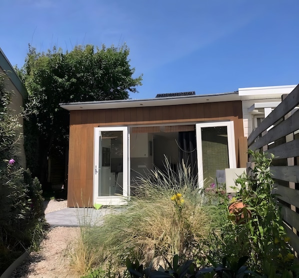 Ein modernes Haus mit Holzfassade, einem Glastür-Eingang und einem Kiesweg, der zur Tür führt.