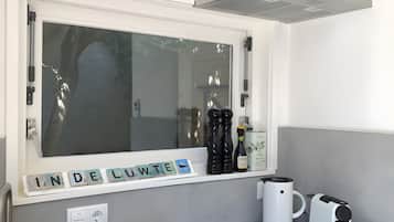 Een moderne keuken met een ingebouwd raam, een koffiezetapparaat en een waterkoker op het aanrecht.