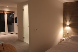 Ein modernes Hotelzimmer mit einem Bett, einem kleinen Nachttisch, einer Nachttischlampe und einer Wandleuchte.