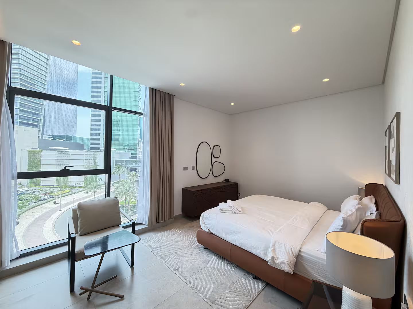 Une chambre d’hôtel moderne avec une grande fenêtre, un lit, un bureau et une chaise.