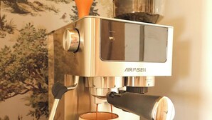 Eine Edelstahl-Espressomaschine mit einer weißen Tasse unter dem Auslauf, auf einer schwarzen Arbeitsplatte platziert.
