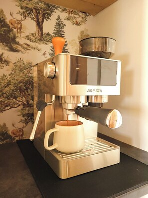Eine Edelstahl-Espressomaschine mit einer weißen Tasse unter dem Auslauf, auf einer schwarzen Arbeitsplatte platziert.