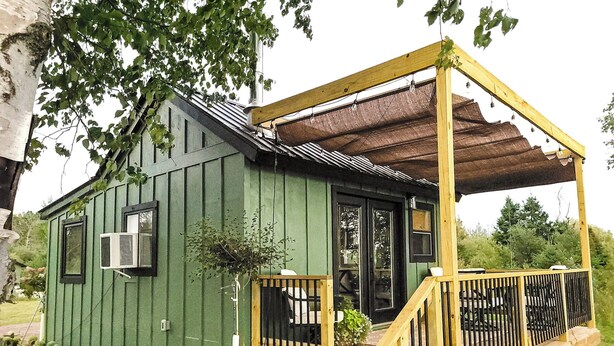 Ein kleines, einstöckiges Holzgebäude mit Veranda und Überdachung.