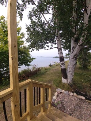 Une terrasse en bois, dotée d’une rambarde, qui mène à une zone herbeuse située au bord d’un plan d’eau.
