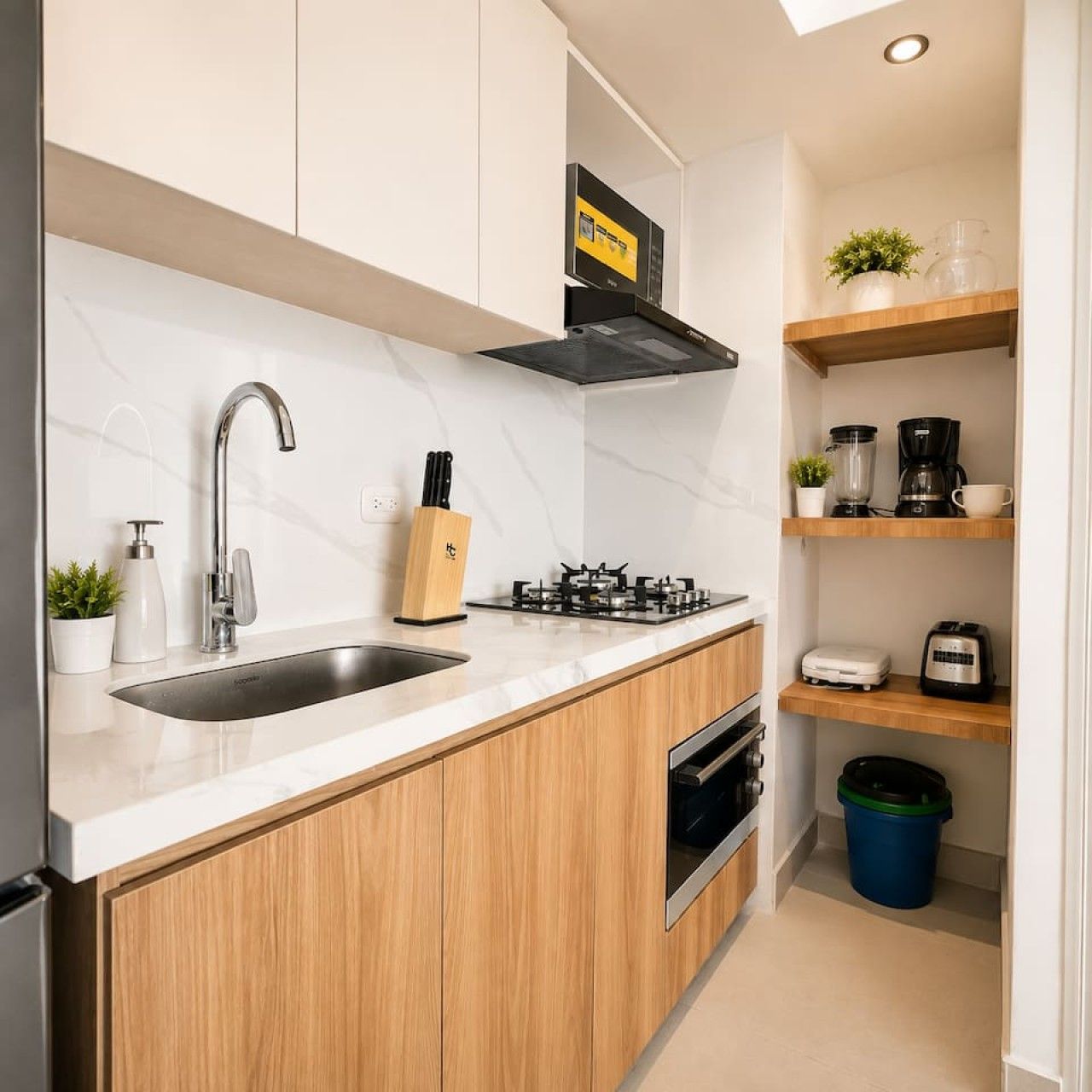 Una cocina moderna con un lavamanos de acero inoxidable, estufa a gas y armarios de madera.