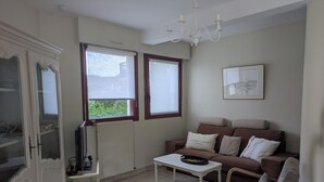 A living room with a sofa, chairs, a coffee table, a television, and a radiator. - Heading to Vannes (Vannes)