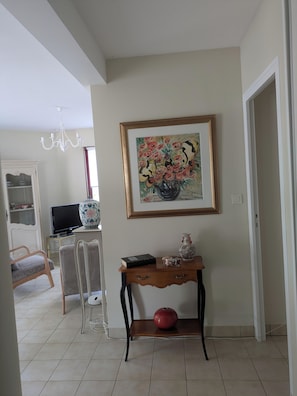 Een woonkamer met een televisie, een vaas en een lijst met een schilderij aan de muur.