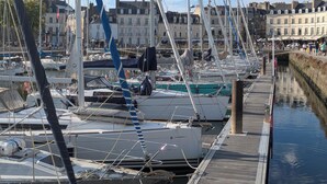 A marina with multiple boats docked, a wooden walkway, and buildings in the background. - Heading to Vannes (Vannes)