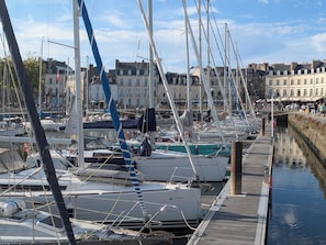 Een jachthaven met meerdere boten afgemeerd, een houten looppad en gebouwen op de achtergrond.