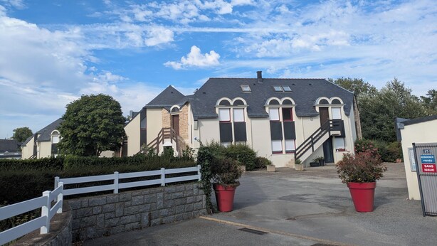 A residential building with a stone facade, multiple windows, and a gated entrance. - Heading to Vannes (Vannes)