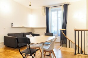 Un salon moderne avec un canapé, des fauteuils, une table et un escalier.