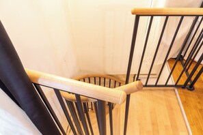 Ein Holzstuhl mit geschwungener Rückenlehne und Metallgestell, platziert in einem Raum mit Holzboden und weißen Wänden.