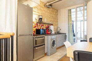 Eine kleine Küche mit Kühlschrank, Backofen, Mikrowelle und Waschmaschine.
