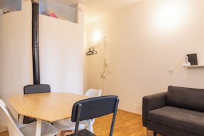 Ein Zimmer mit einem Holztisch, zwei Stühlen, einer Couch, einem Heizkörper und einem Wandheizgerät.