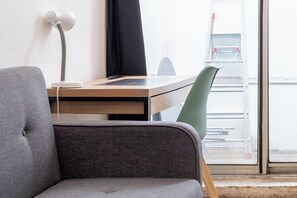 A modern office space with a desk, chairs, a lamp, and a window with a view. - Chic Apartment Near Ménilmontant & Père Lachaise (Paris)